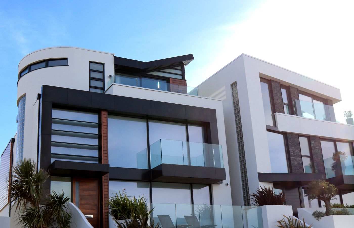 Modern waterfront home with glass balconies and palm landscaping