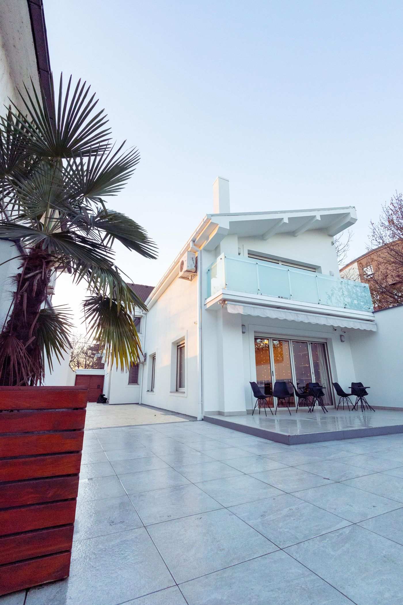 Bright white house with wide stone terrace and palm tree